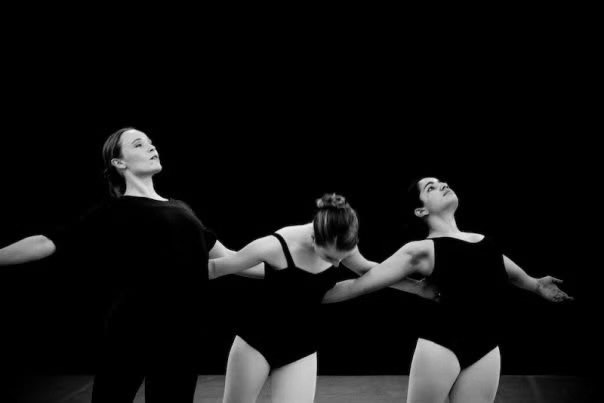 Three dancers sharing an expressive ensemble movement