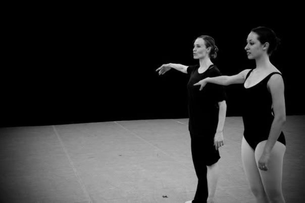 Two dancers extending their arms in rehearsal