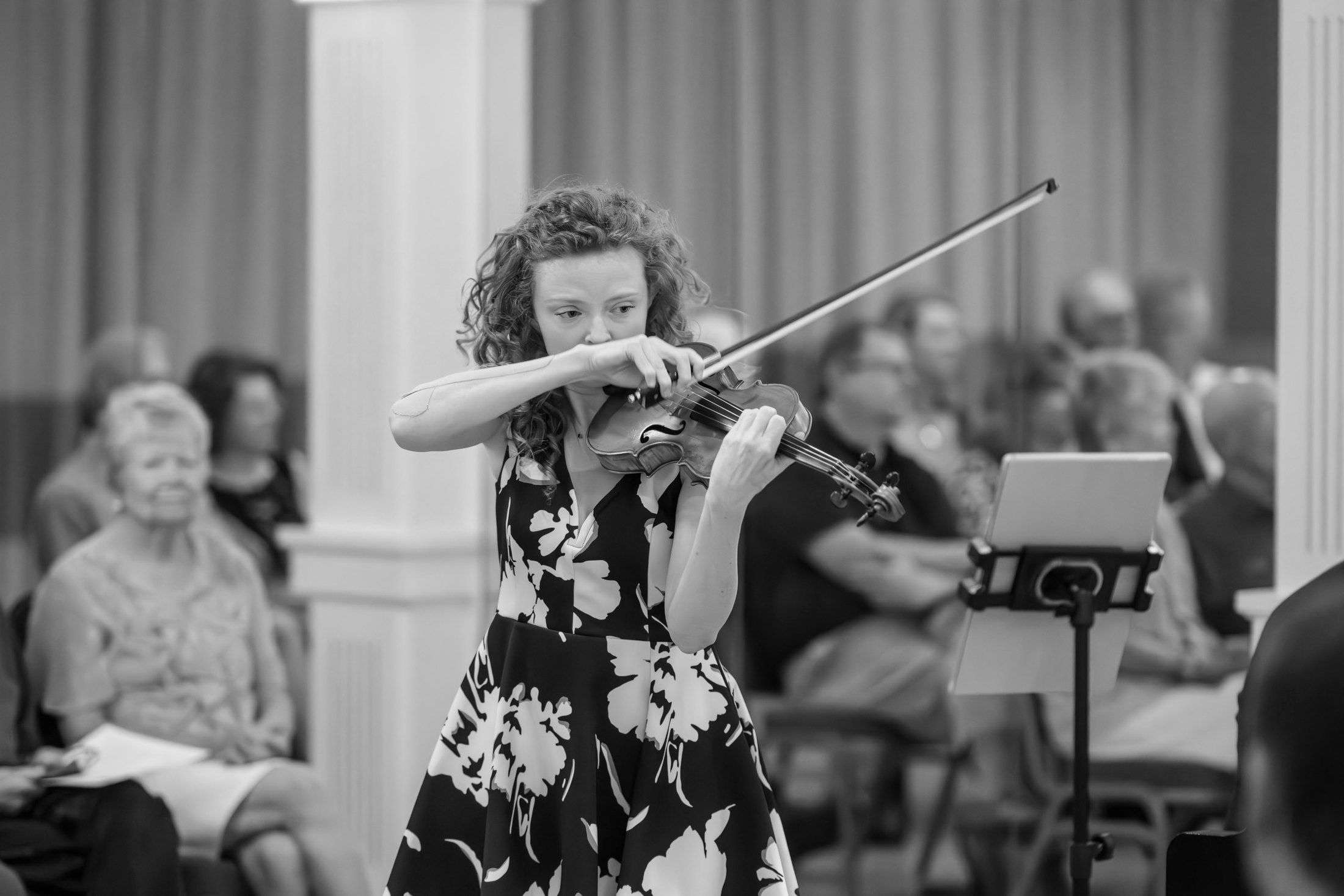 A violinist performing before a seated audience